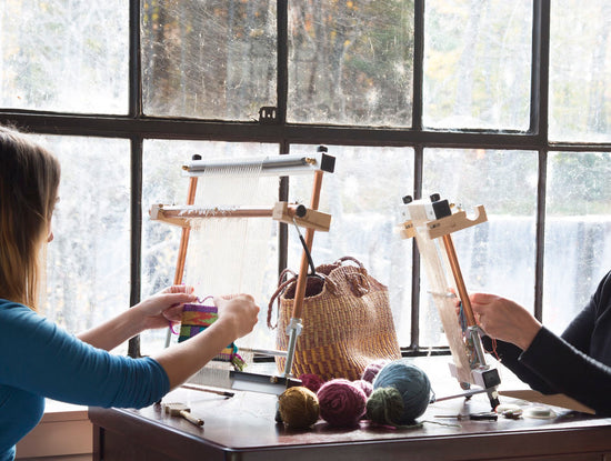 Two people weaving on upright looms.